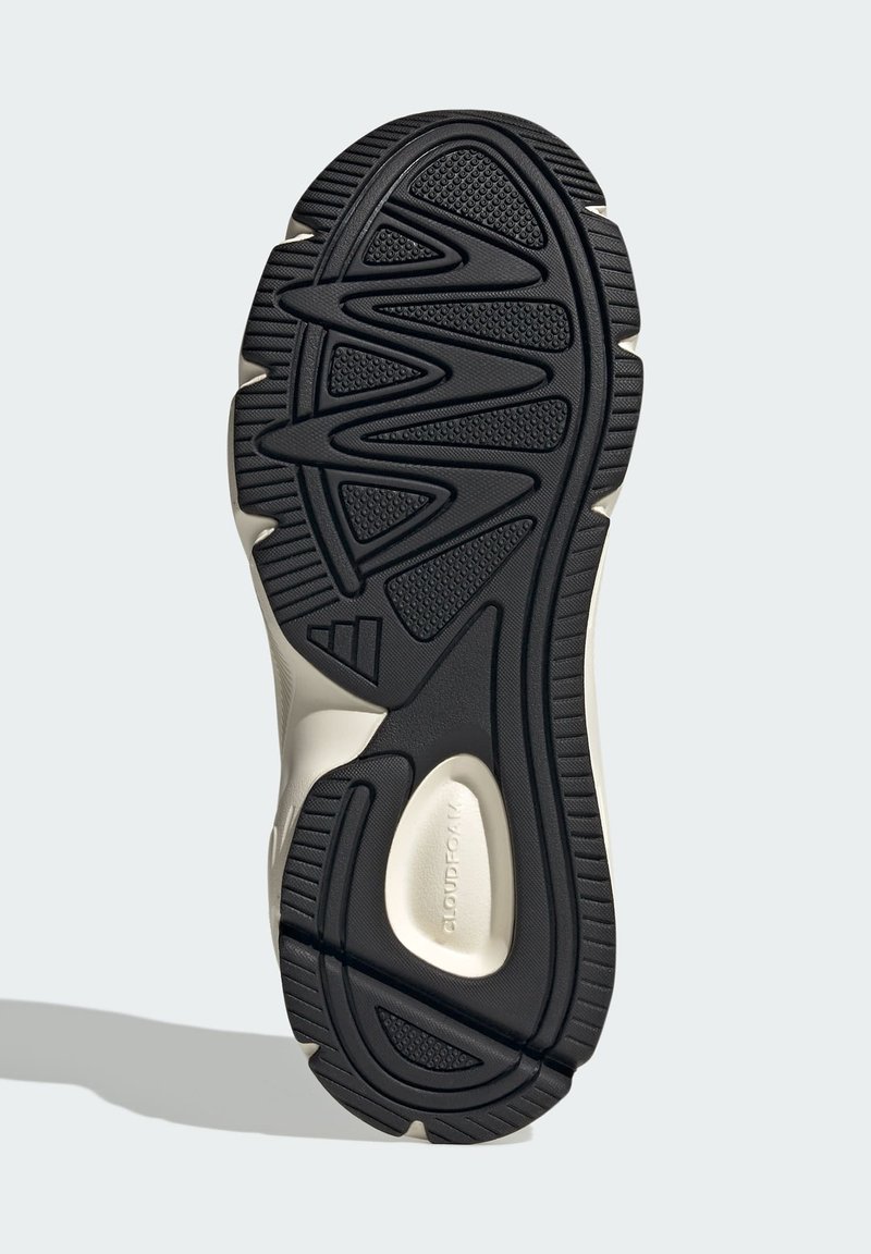 Zwarte rubberen buitenzool met een textuurpatroon voor grip, met een golvend ontwerp en verstevigde gebieden. Lichtgekleurde tussenzool verhoogt de duurzaamheid.