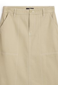 Beige kjol med en slät textur, med dubbla fickor, kontrasterande vit sömnad och framknäppning.