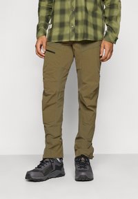 Pantalons d'extérieur khaki à coupe slim, fabriqués en tissu léger. Dotés de poches zippées et d'une construction durable. À associer avec des chaussures de randonnée noires.