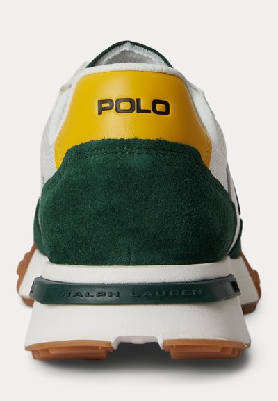 Valge tossu tagantvaade, millel on roheline seemisnahast kand, kollane nahast plaastritükk, millel on kiri "POLO", ning valge tald, mille ääres on kandmisel reljeefne kiri "RALPH LAUREN".