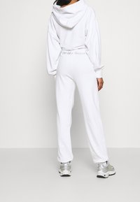 Witte hoodie met een oversized ontwerp en kangoeroezak, gecombineerd met witte sweatpants met de borduursel "Freshly Squeezed" op de tailleband.