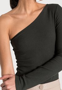 Asymmetrisches Langarmoberteil aus dunkelgrünem geripptem Stoff, mit einer eng anliegenden Silhouette und einem schulterfreien Design.