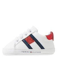 Zapatilla de cuero blanco con detalles en purpurina roja y azul, cordones redondos y suela texturizada. Logotipo "TOMMY HILFIGER" en el lateral.