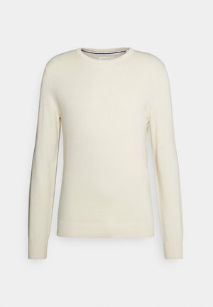 Krämfärgad rundhalsad tröja med långa ärmar, ribbade muddar och nederkant. Tillverkad av mjukt stickat tyg utan mönster eller dekorationer.