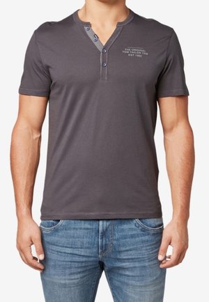 Grå kortærmet henley-trøje med to-knaps åbning og diskret logo på brystet; lavet af blødt bomuldsstof med en afslappet pasform.