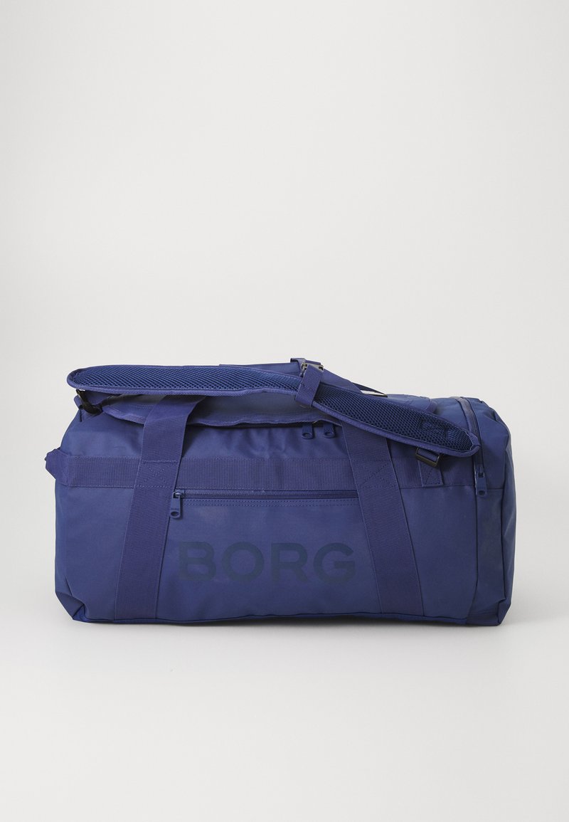 Tamsiai mėlyna sportinė kuprinė, pagaminta iš tvirtos medžiagos, su užtrauktuku, reguliuojama juosta ir išryškintu "BORG" logotipu šone.