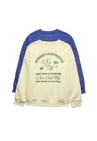 Two crewneck sweatshirts, one cream with green text about Sydney Australia, layered over a solid blue sweatshirt, displayed flat on white background.