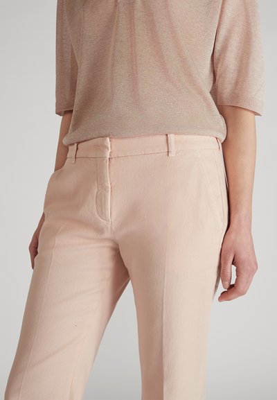 Pantalons rose clair en tissu texturé, avec une taille ajustée, des poches latérales et des coutures soignées. Design doux et décontracté.