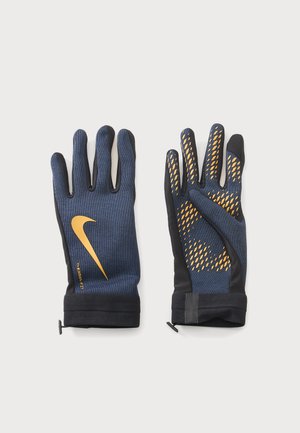 Paire de gants Nike bleu marine et noir avec logo jaune et points d’adhérence, conçus pour temps froid et usage actif.