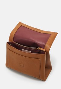 Borsa a tracolla in pelle color tan con finitura testurizzata; presenta un interno color bordeaux, una tasca con zip e una tasca a scomparsa sul davanti.