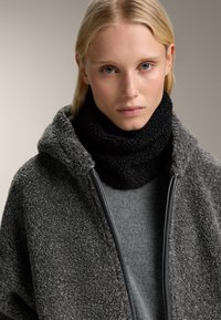 Jachetă din fleece gri cu o suprafață texturată, cu guler negru din tricot. Sub ea se află un pulover gri neted. Detaliile cu fermoar sunt vizibile.