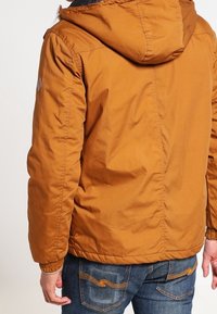 Brun isoleret jakke med hætte, med elastiske manchetter, en glat tekstur og et logo patch på den øverste ryg. Matcher med denim jeans.
