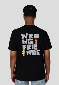 Černé bavlněné tričko s nápisem "WRONG FRIENDS" v šedé barvě a dvěma kreslenými postavičkami v oranžové a žluté na zádech.