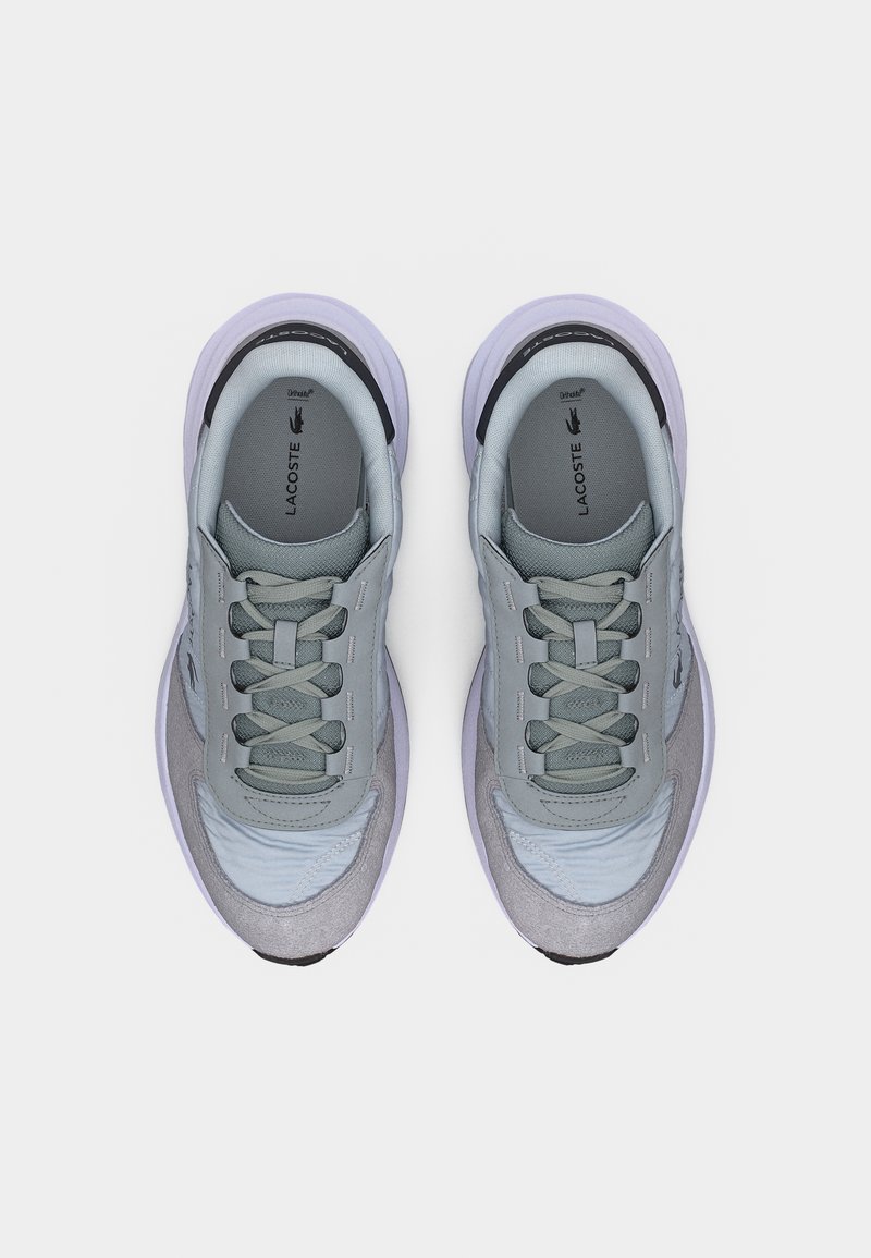 Paar graue und hellviolette Lacoste-Sneaker mit Schnürsenkeln, Mesh- und Wildlederpaneelen, von oben auf weißem Hintergrund betrachtet.