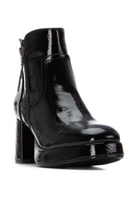 Bota corta de charol negro con un acabado brillante, puntera redonda, cremallera lateral y un tacón grueso con una suela de plataforma.
