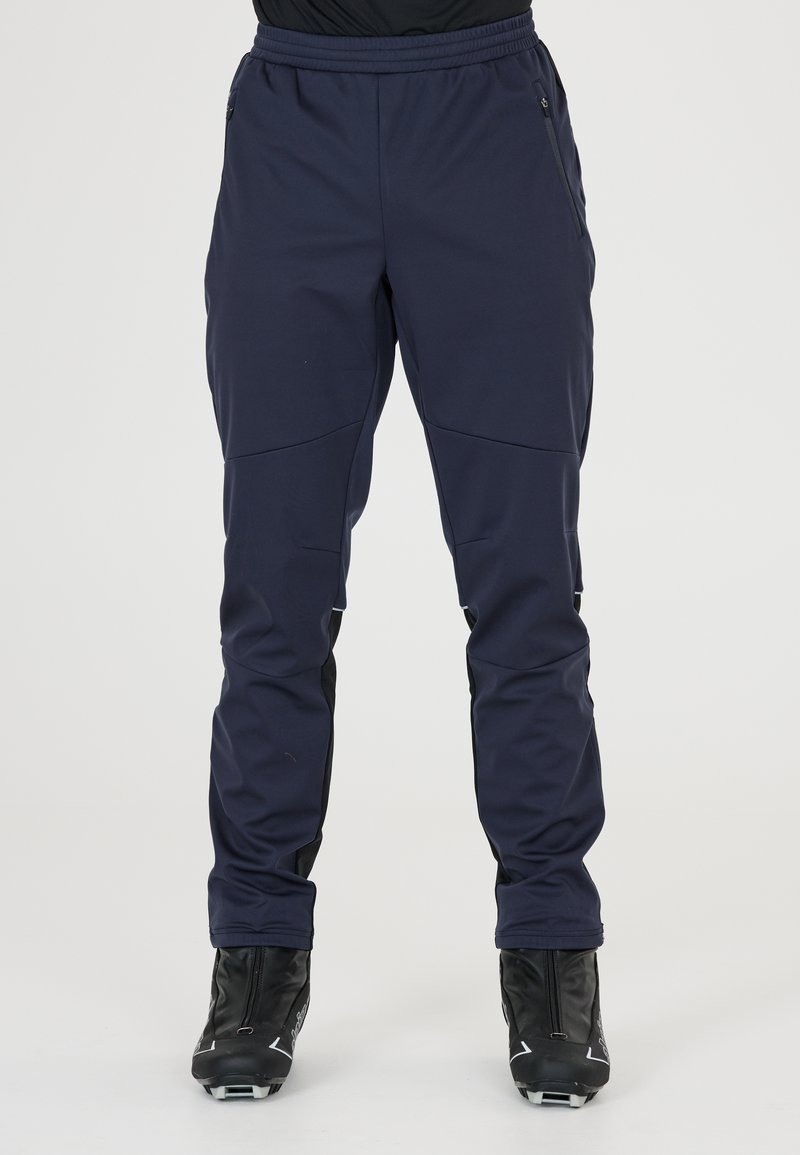 Marina skidbyxor med elastisk midja, fickor med dragkedja och avsmalnande passform. Materialet är slätt med hållbara detaljer vid anklarna.