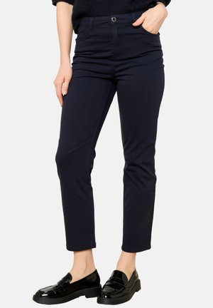 Pantaloni elastici blu navy con vestibilità slim, presentano una vita alta, tasche frontali e una texture liscia, abbinati a mocassini neri lucidi.