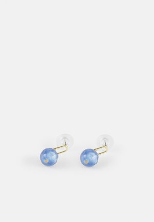 Paired boucles d'oreilles clous avec pierres bleues rondes et accents en métal de couleur or sur un fond blanc uni.