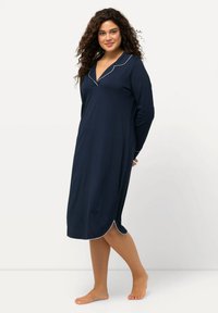 Camicia da notte navy a maniche lunghe con piping bianco, scollo a V, fessure laterali e una vestibilità rilassata, realizzata in tessuto morbido e leggero.