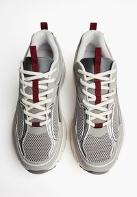 Gray athletic shoes featuring mesh and synthetic materials, front lacing, padded collar, and a maroon accent on the heel loop.