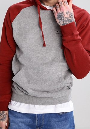 Grauer und roter Hoodie mit Kängurutasche, verstellbarem Kordelzug und gerippten Bündchen. Aus weichem Stoff mit kontrastierenden Ärmeln gefertigt.