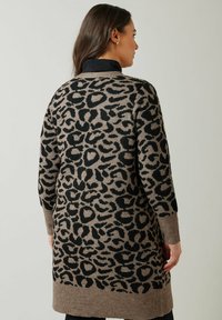 Leopardikuosiset neuletakki, jossa on pehmeä, neulekudos. Perusväri on beige, ja siinä on mustia eläinkuvioita. Pitkät hihat ja puolipitkä pituus.