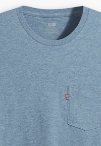 T-shirt Levi's bleu chiné avec col rond et petite poche poitrine avec une étiquette rouge Levi's sur le côté droit.