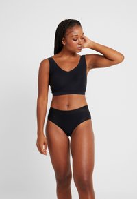 Svart sømløs crop top med brede stropper og V-hals, kombinert med høy midje bikini underdeler, begge i glatt, elastisk stoff.