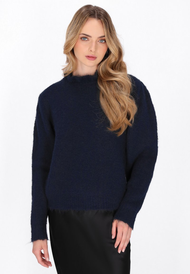Dunkelblauer Pullover aus weichem, flauschigem Material. Verfügt über einen hohen Kragen, lange Ärmel und leicht ausgefranste Saumdetails.