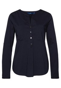 Chemise bleu marine à manches longues avec col en V, deux poches sur la poitrine et fermeture par boutons. Tissu lisse avec une coupe structurée et une texture subtile.