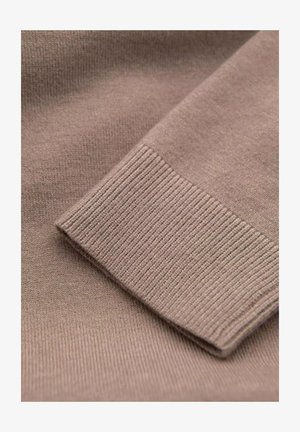 Ruskea neulekangas, jossa on sileä pinta ja ribatty rakenne hihansuussa, esittelee taitettua reunaa siistin viimeistelyn saavuttamiseksi.