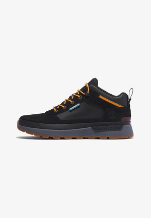 Czarno-szary niskoprofilowy sneaker z pomarańczowymi sznurowadłami, uchwytem na pięcie oraz brązową gumową podeszwą.