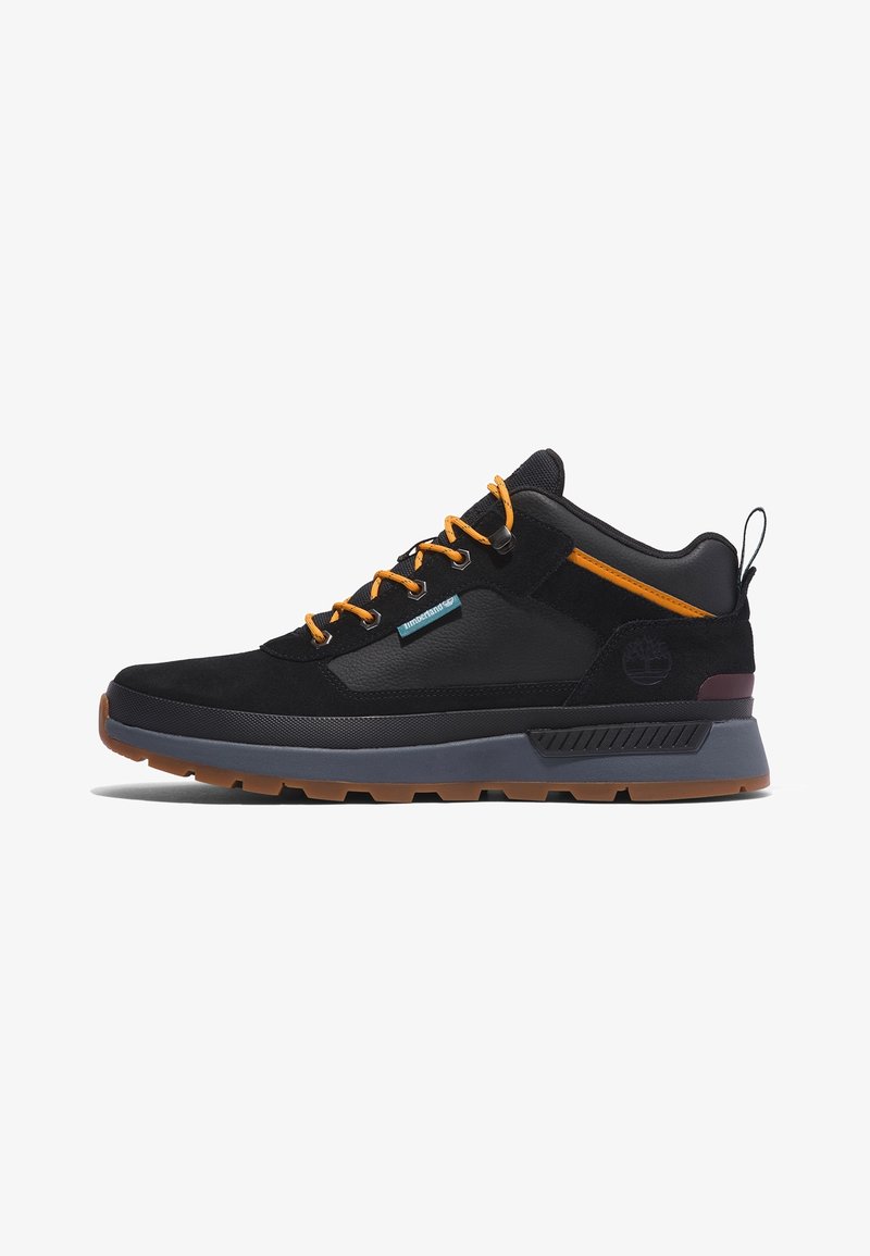 Baskets basses noires et grises avec des lacets orange, une languette au talon et une semelle en caoutchouc marron.