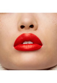 Labios rojos vibrantes con una textura suave y mate, que muestran contornos definidos y un sutil brillo. Tono de piel natural alrededor de los labios.