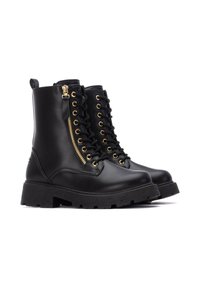 Botas de tobillo de cuero negro con suela gruesa, herrajes dorados, cordones en la parte frontal y un zip lateral para un fácil acceso.