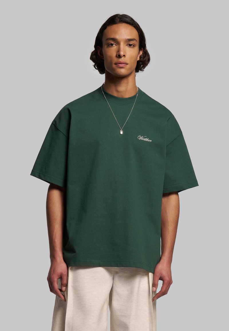 Grön oversized t-shirt i bomull med rund halsringning och korta ärmar, med vit broderad text på bröstet.