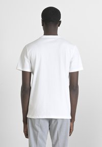 Camiseta de algodón blanca con cuello redondo y mangas cortas, con una parte trasera lisa y un corte holgado. Sin marcas ni patrones visibles.