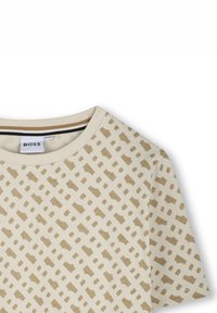 Beige t-shirt featuring a geometric pattern in light brown. Crew neck design with short sleeves and subtle accent stitching details.