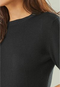 Schwarzer Ribpullover mit eng anliegendem Design. Verfügt über einen runden Ausschnitt und eine strukturierte Oberfläche, die vertikale Streifen betont.