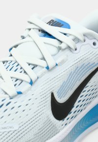 Αθλητικό παπούτσι σε ανοιχτό μπλε χρώμα με υφασμάτινη επάνω πλευρά, λευκά κορδόνια, μαύρο σήμα Nike και ανατομική σόλα με γκρι σκαλίσματος μπλε λεπτομέρειες.