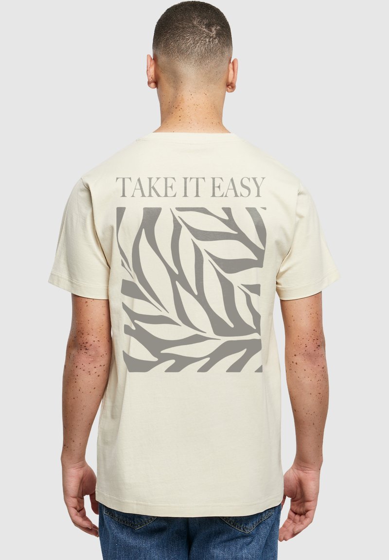 Kreemivärvi puuvillane t-särk, millel on hall lehe muster ja seljal tekst "TAKE IT EASY". Klassikaline ümar kaelus.