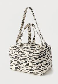 Τσάντα duffel από καμβά με μαύρο και κρεμ σχέδιο τίγρης, δύο κοντές λαβές, ρυθμιζόμενο λουρί και κλείσιμο με φερμουάρ. Υφασμάτινη υφή.