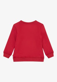 Rød langermet genser med ribbestrikket hals og ermer. Myk tekstur, ensfarget og en avslappet passform. Ingen synlige mønstre eller tilleggdetaljer.