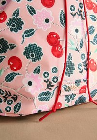 Roze stoffen tas met een bloemenpatroon van rode kersen, zwarte bloemen en groene bladeren. Rood trekkoord en logo labeldetail.