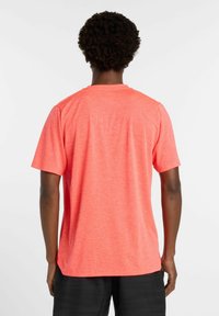 Kortærmet t-shirt i lys koralfarve med en glat tekstur og en afslappet pasform. Bagsiden viser en rund halsudskæring og syningsdetaljer.