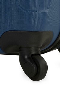 Maleta texturizada azul con una carcasa dura y duradera, que cuenta con una base y ruedas de plástico negro para una movilidad suave.