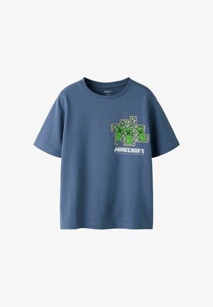 Camiseta azul de manga corta con diseño de Minecraft que presenta tres personajes Creeper verdes pixelados y el logo de Minecraft en el pecho.