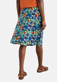 Floral print skirt in blue, green, orange, and white. A-line shape with a hemline just above the knee. Lightweight fabric, worn with brown sandals.