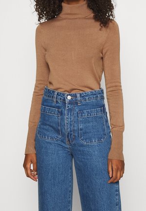 Brown turtleneck sweater in a soft knit paired with high-waisted blue denim jeans featuring large pockets and a button front closure.