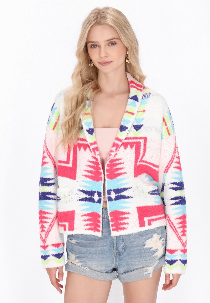 Fuzzy oversize kofta i vitt med rosa, blå och gröna geometriska mönster; öppen framsidan, långa ärmar och fickor.